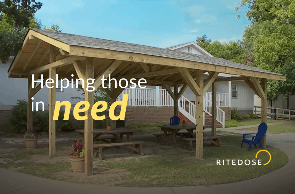 exterior daytime photo of a wooden pavilion with text overlay: helping those In need