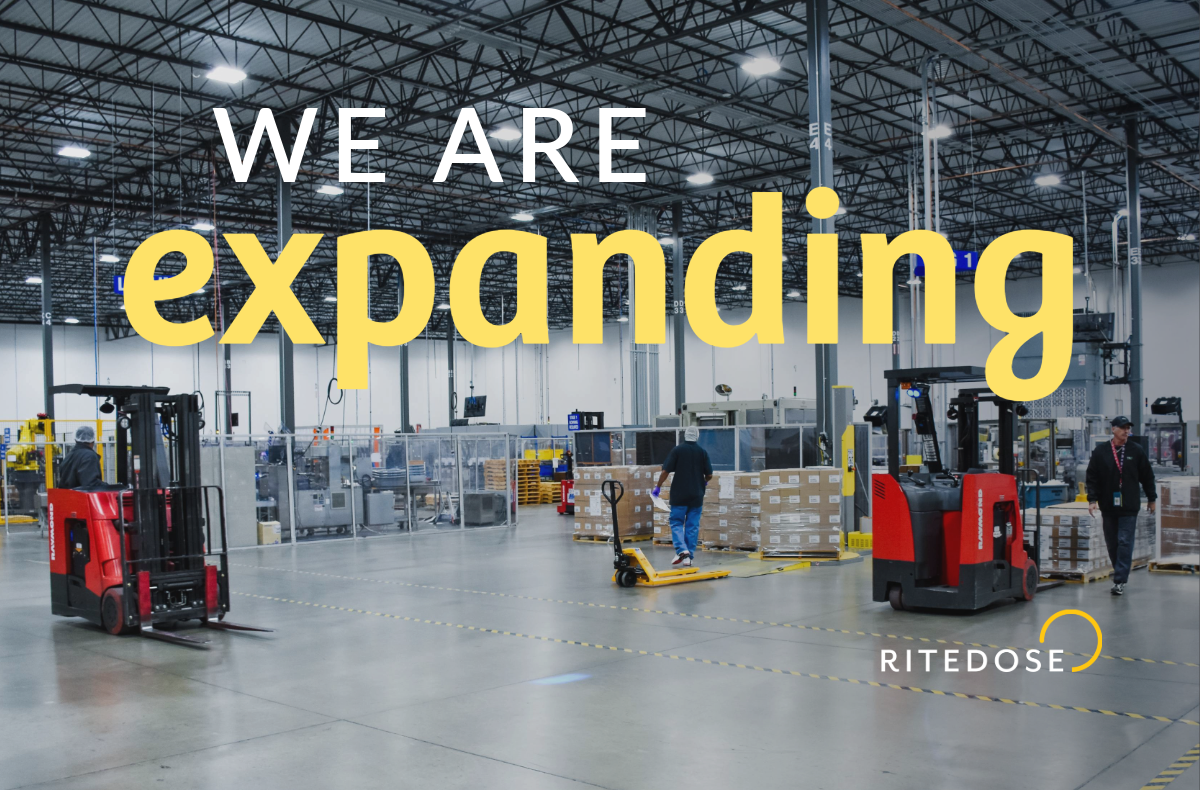 interior of large warehouse with forklifts in foreground and text overlay: we are expanding